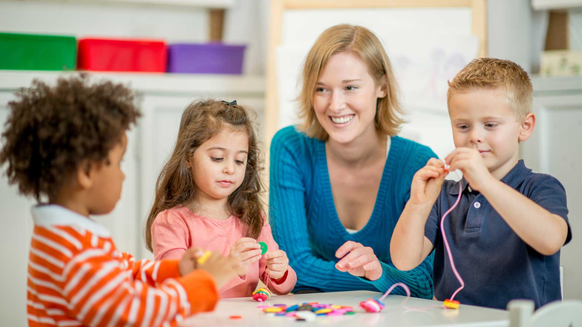 Occupational therapist helping 3 children thread things on string